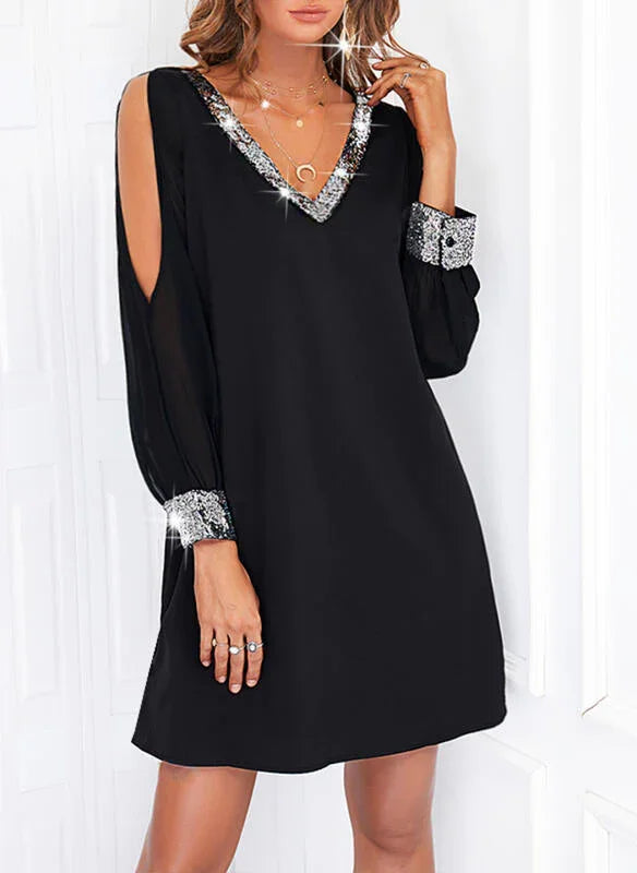Woman wearing black mini dress with silver sequin V-neck and cuff details, sheer open sleeves