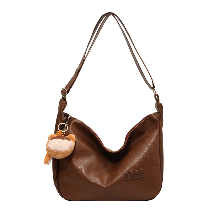 Brown leather shoulder handbag with adjustable strap and cute bear face keychain accessory