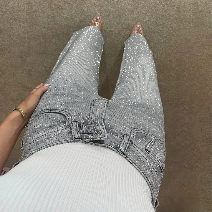 Woman wearing high-waisted silver sequin jeans with white ribbed top and clear heels