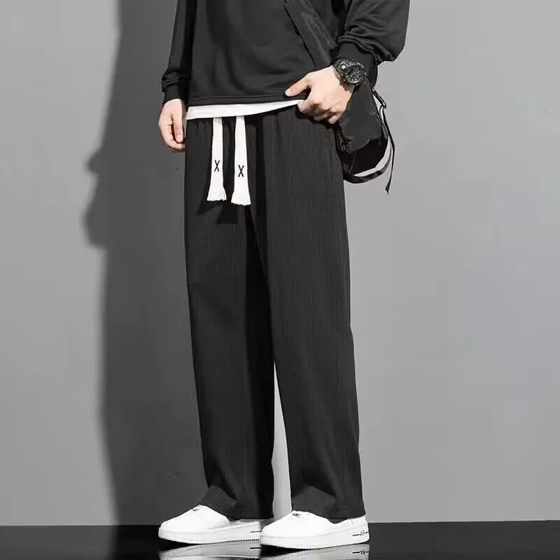 Men's black wide-leg pants with white drawstrings paired with white sneakers and black top