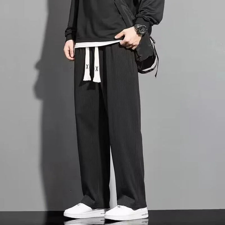 Men's black wide-leg pants with white drawstrings paired with white sneakers and black top