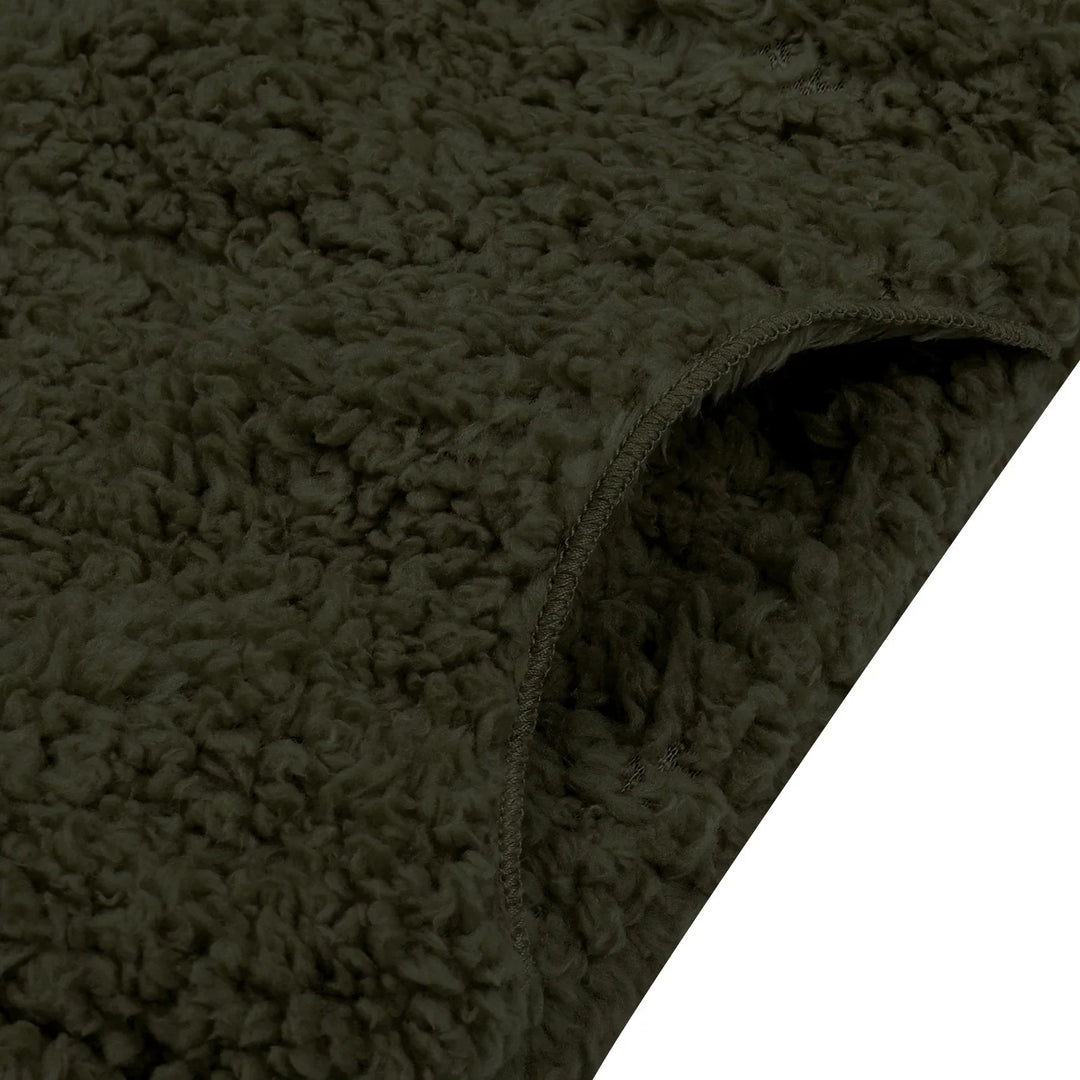 Close-up of dark green sherpa fleece fabric with curled texture and stitched edge