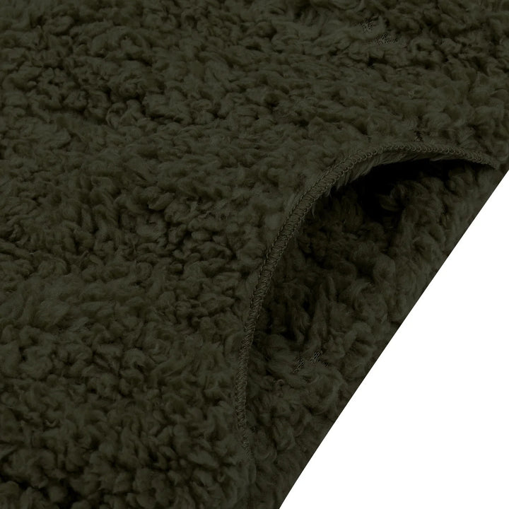 Close-up of dark green sherpa fleece fabric with curled texture and stitched edge