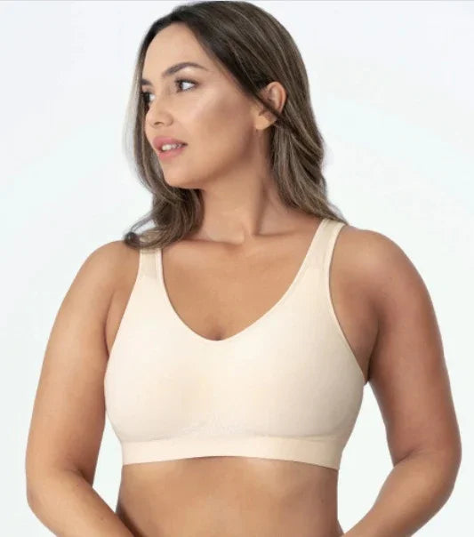 Woman wearing a beige seamless bra, looking to the side, on a white background
