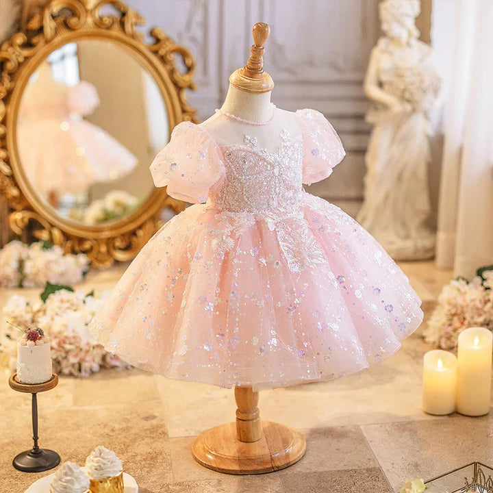 Pink toddler princess dress with puff sleeves and floral sequins on wooden mannequin