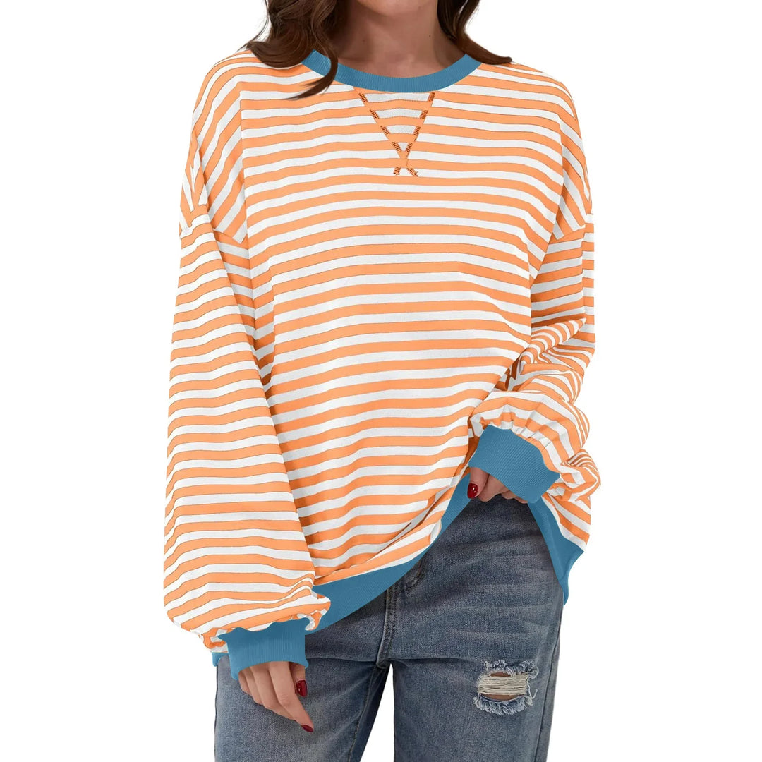 Casual orange and white striped long-sleeve sweatshirt with blue cuffs and neckline worn with ripped jeans