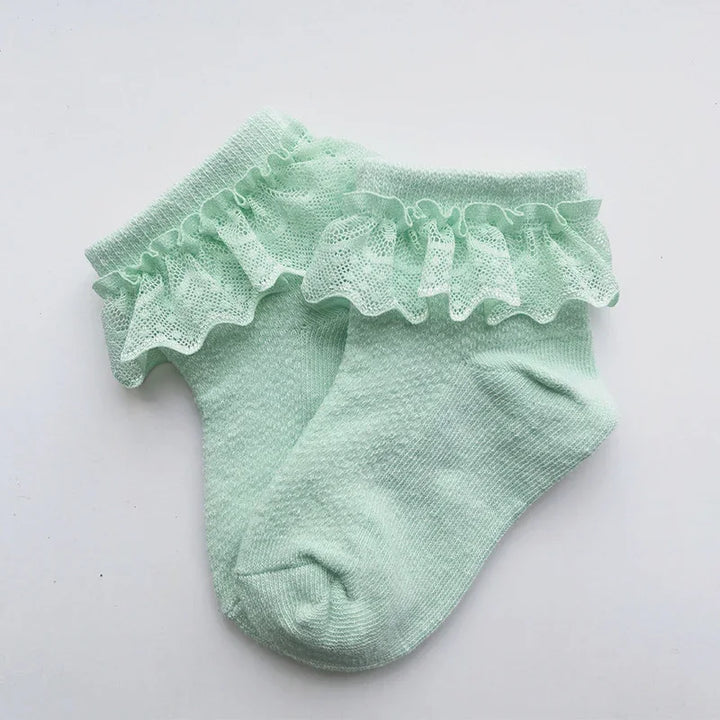mint green baby socks with delicate lace ruffle trim on white background