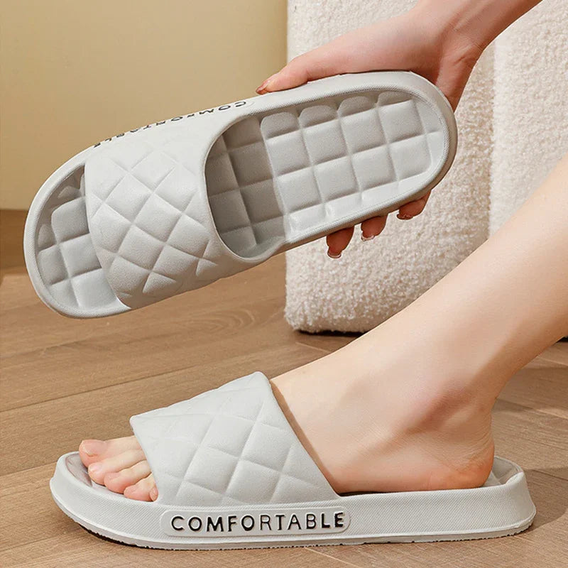 Light gray cushioned open-toe slippers with quilted design and comfortable sole, one worn on foot