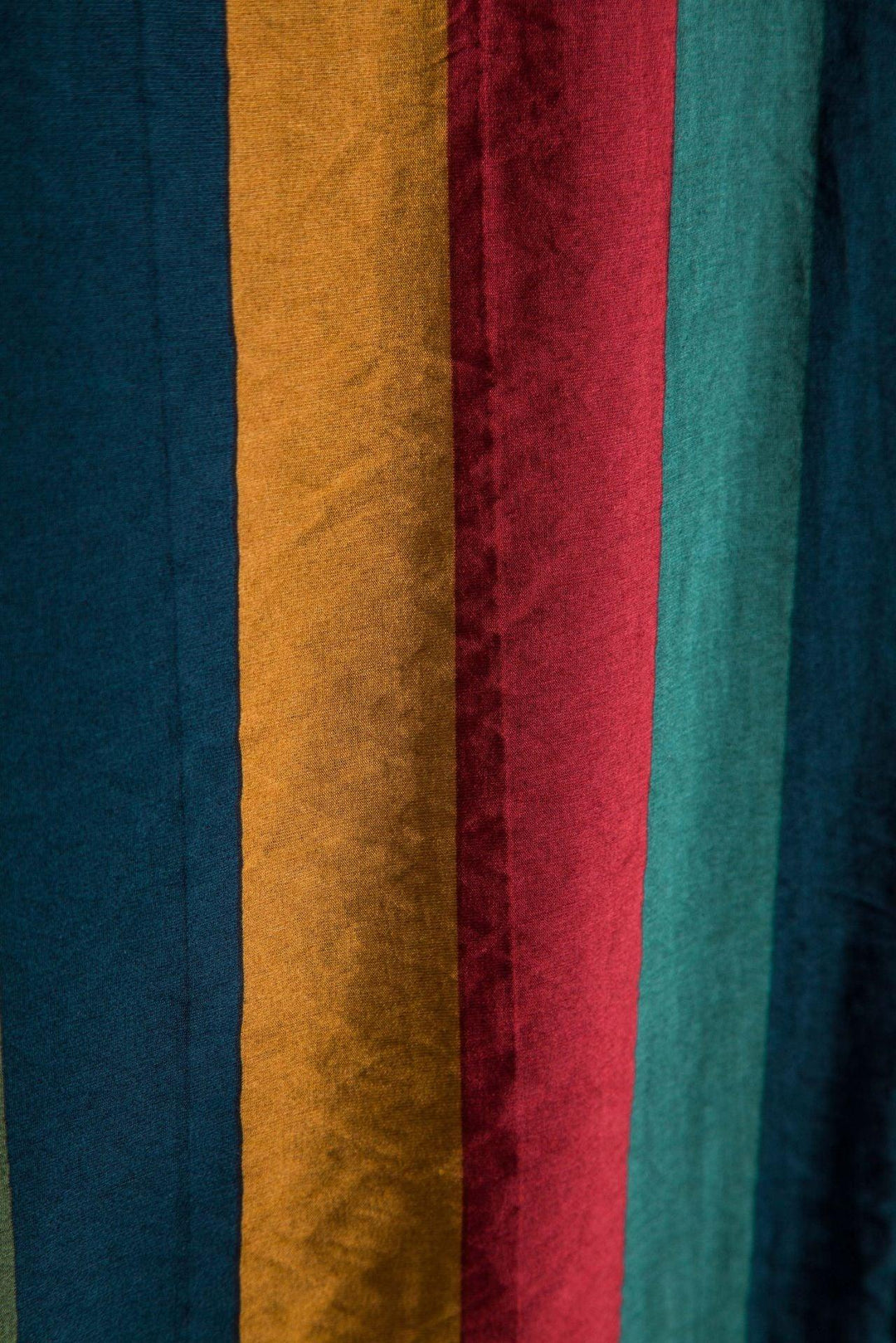 Close-up of vertical soft fabric stripes in teal, mustard, red, and green colors