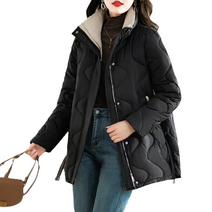 Woman wearing black quilted winter coat with beige collar, blue jeans, holding brown handbag