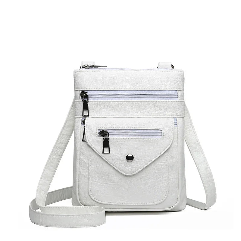 White crossbody bag with multiple zippered pockets and adjustable strap on white background