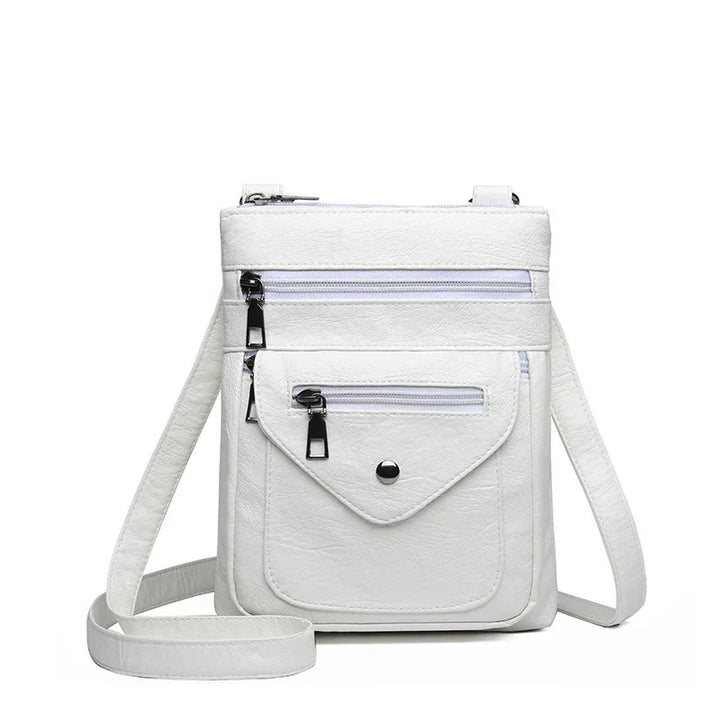 White crossbody bag with multiple zippered pockets and adjustable strap on white background