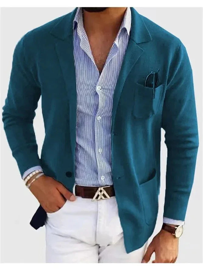 Man wearing teal blazer over striped blue shirt and white pants with brown belt and wristwatch