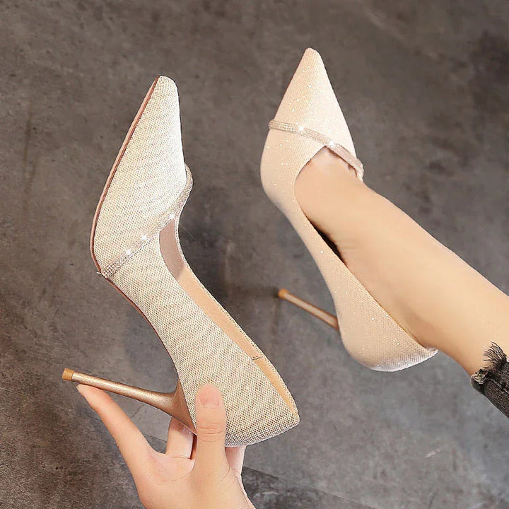 Sparkling beige high-heeled pumps with pointed toes and thin stiletto heels on gray floor