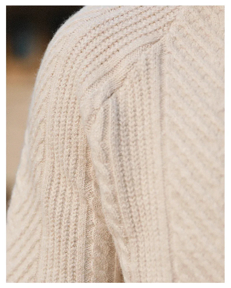 Close-up of beige cable knit wool sweater shoulder, showing textured knit pattern and soft fabric