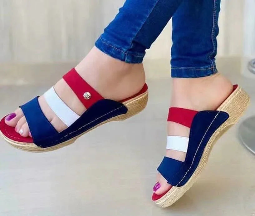 Blue, white, and red wedge sandals with woven textured soles worn with blue jeans