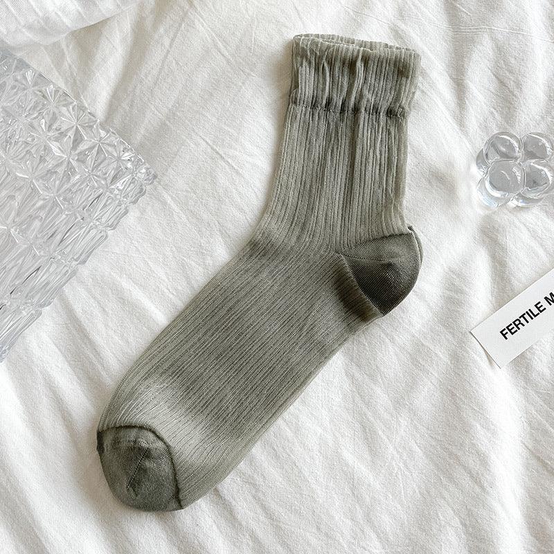 Single gray ribbed ankle sock with darker toe and heel on white fabric background