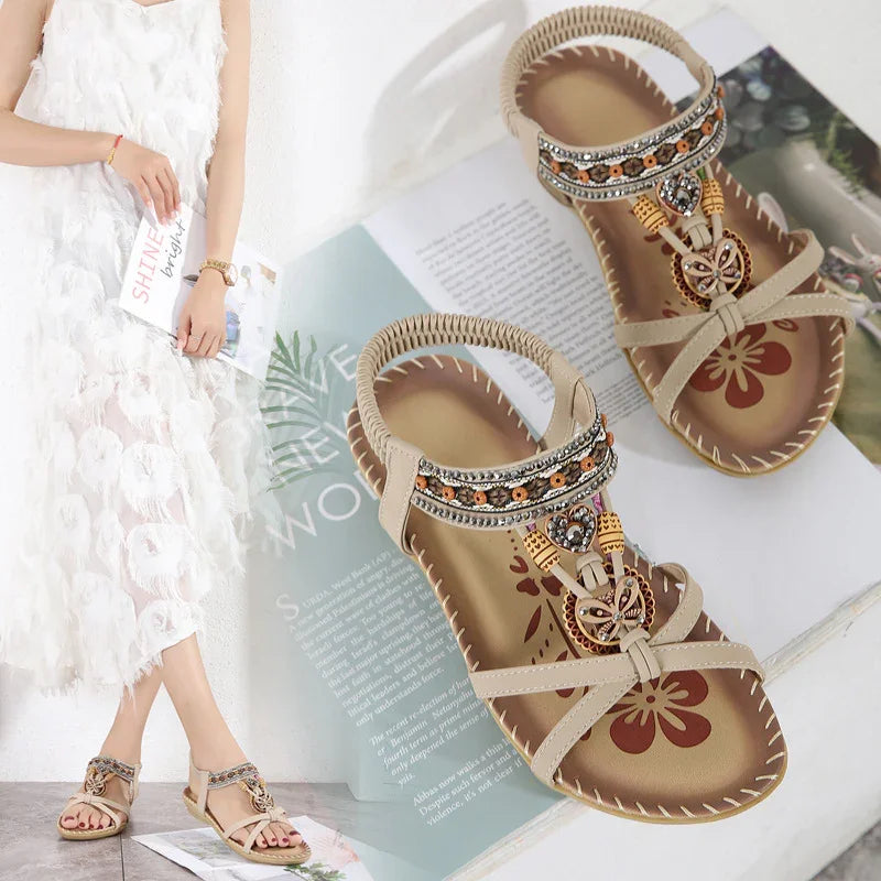 Beige women's sandals with floral and heart bead embellishments on tan insoles and decorative stitching