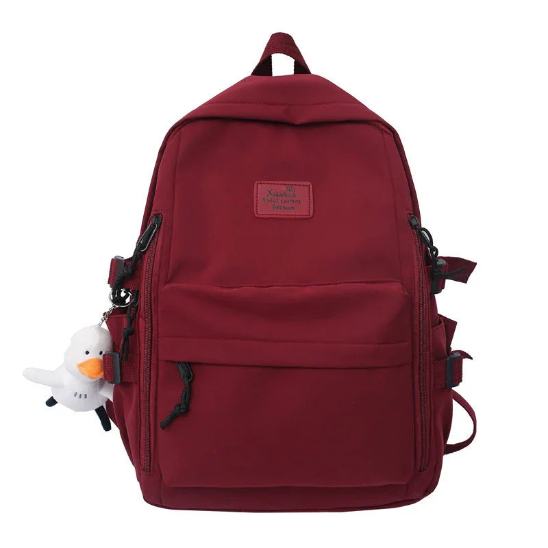 Maroon backpack with front pocket and plush white duck keychain hanging on the side