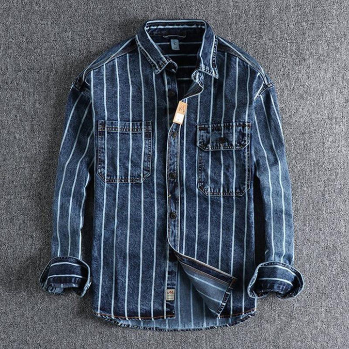 Men's blue denim shirt with vertical white stripes and two chest pockets on gray carpet