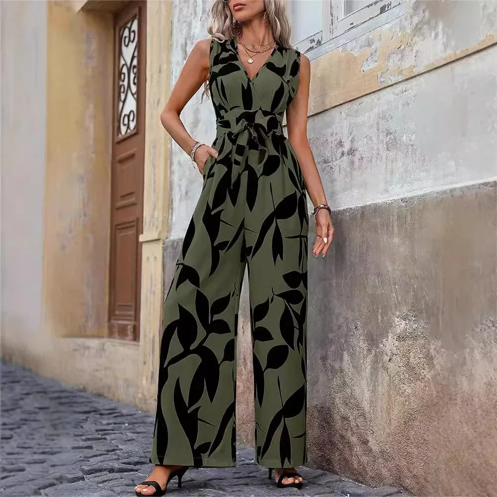 Woman wearing sleeveless olive green jumpsuit with black leaf print, standing on cobblestone street