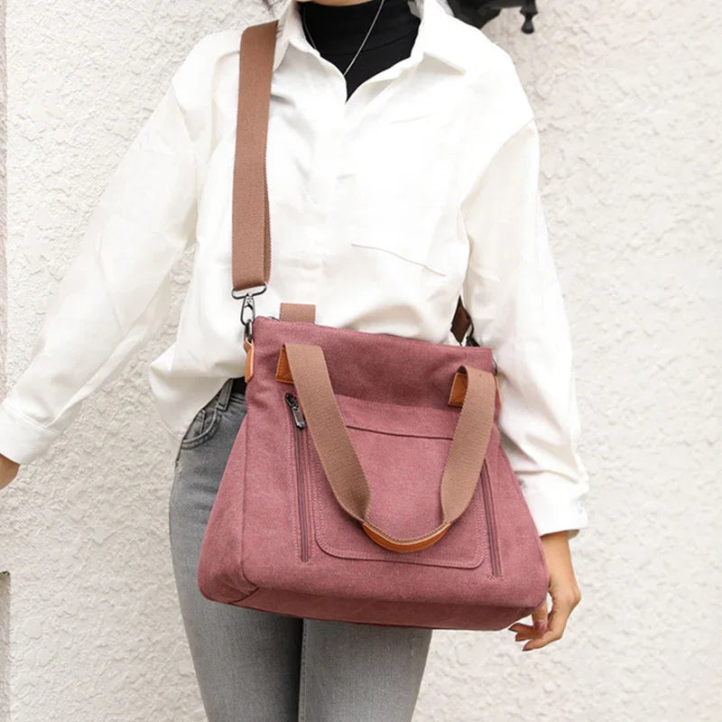 Woman wearing white shirt and gray jeans carrying large pink suede shoulder bag with brown straps