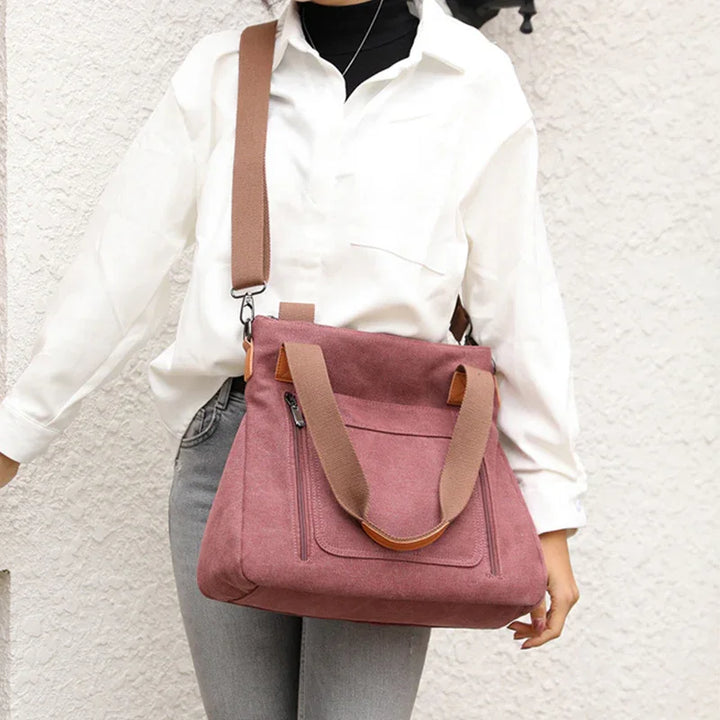Woman wearing white shirt and gray jeans carrying large pink suede shoulder bag with brown straps