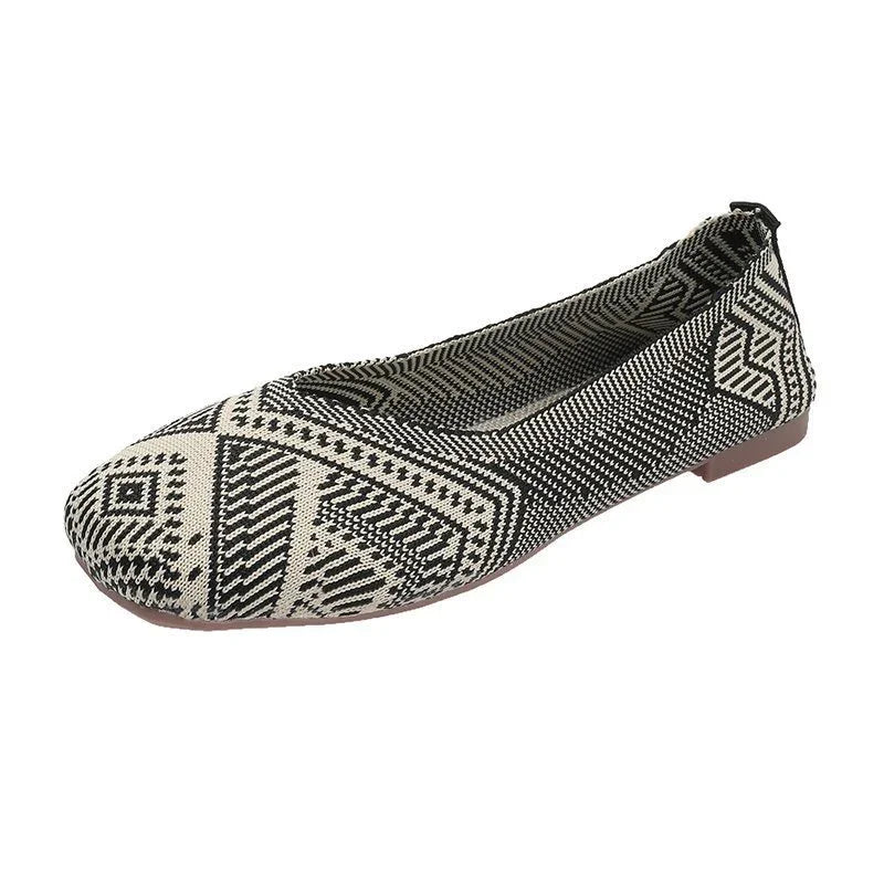 Black and white patterned women's flat shoe with geometric tribal design and low brown sole