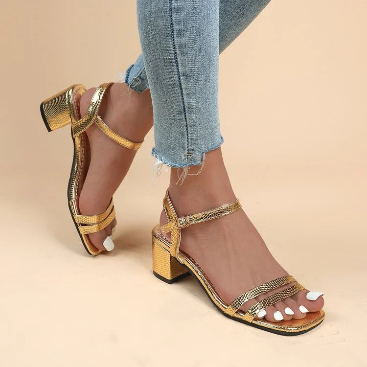 Woman wearing gold block heel sandals with ankle straps and frayed hem blue jeans