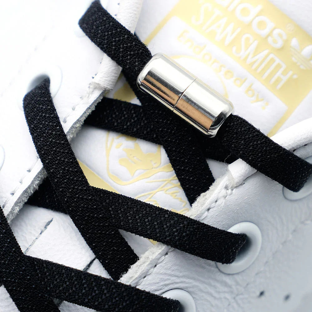 Close-up of Adidas Stan Smith sneaker with black shoelaces and a silver lace lock
