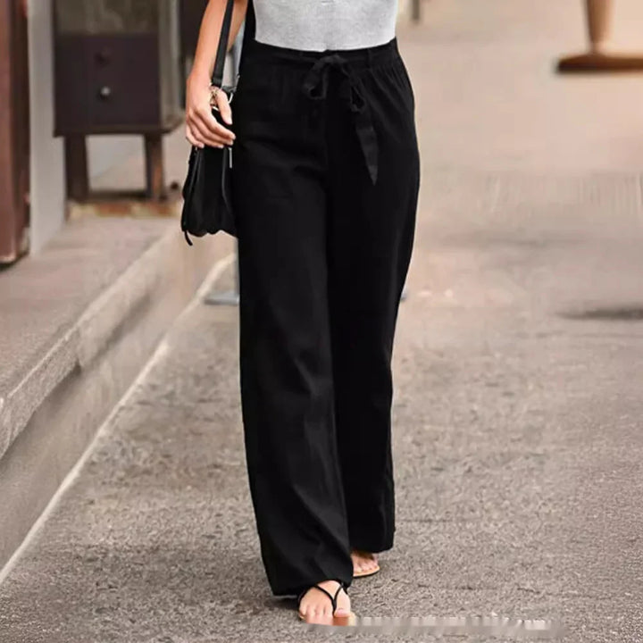 Woman wearing black wide-leg pants with a drawstring waist walking on a city street