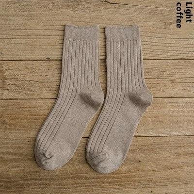 pair of light coffee colored ribbed crew socks on wooden surface
