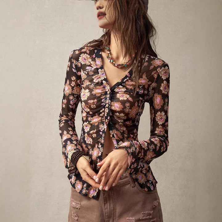 woman wearing floral sheer long-sleeve buttoned top and distressed pants with beaded necklace and bracelets