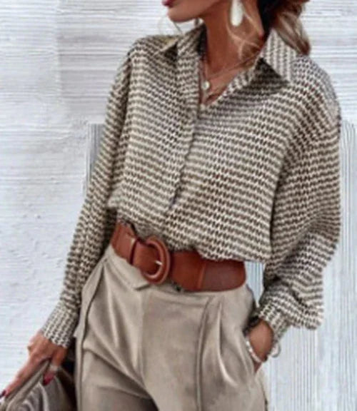 woman wearing houndstooth patterned blouse tucked into high-waisted beige pants with brown belt