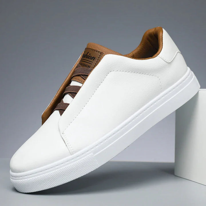 White casual sneaker with brown leather accents and brown laces on grey background