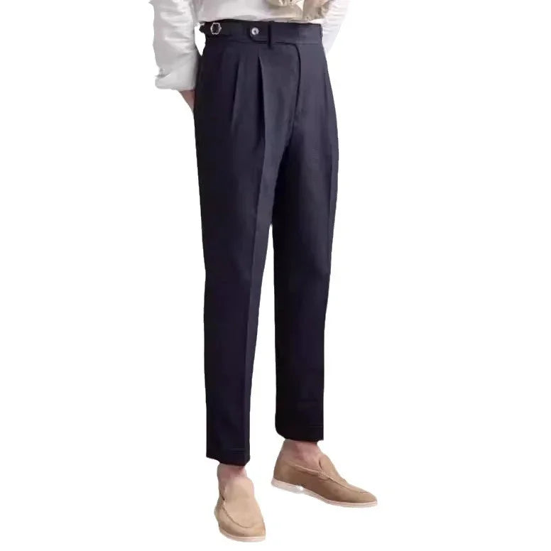 Men's black tapered dress pants with pleats, button strap detail, paired with beige loafers