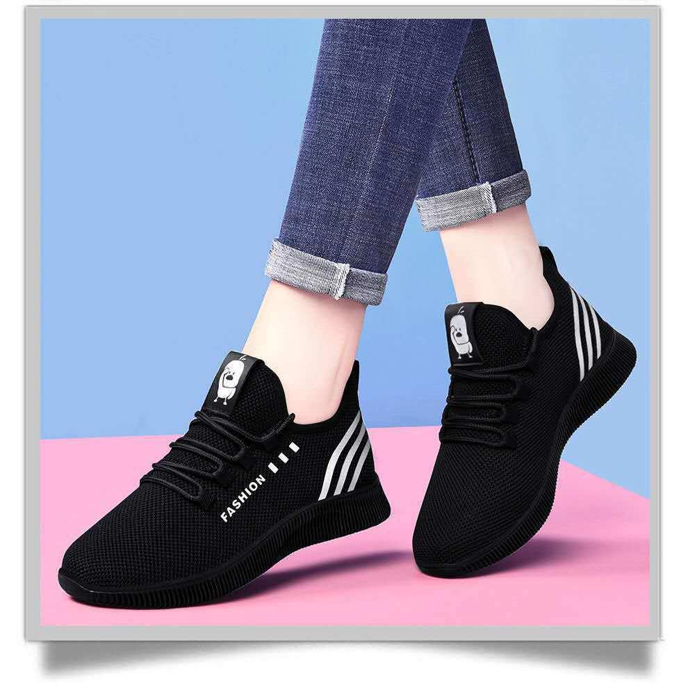 Black fashion sneakers with white stripes worn with rolled-up blue jeans on pink and blue background