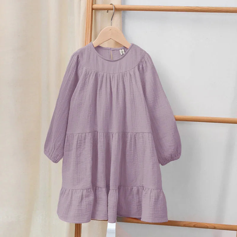 Lilac long-sleeve baby girl dress with ruffled hem hanging on wooden hanger