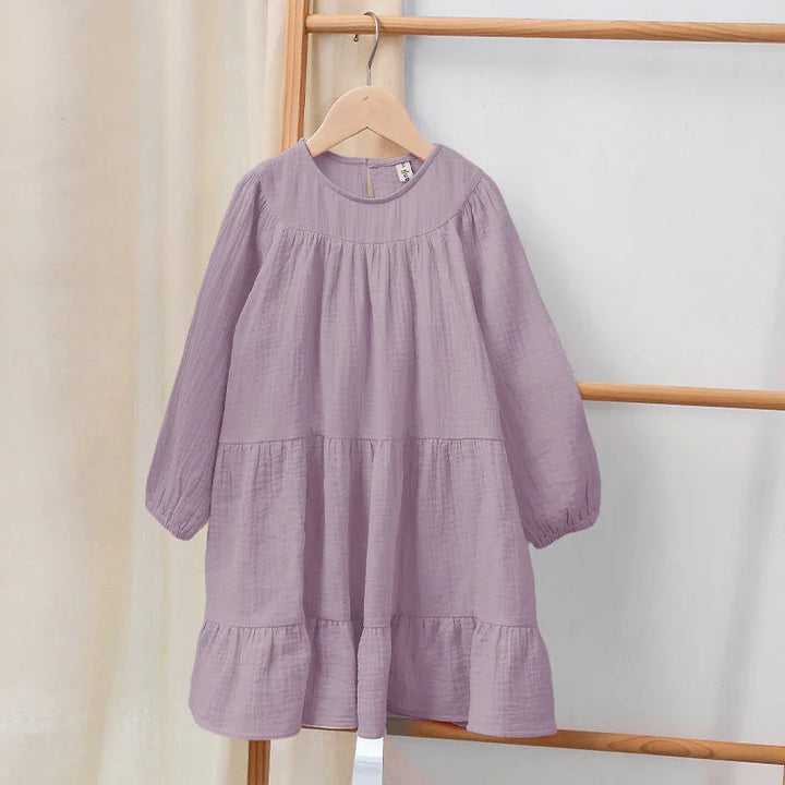 Lilac long-sleeve baby girl dress with ruffled hem hanging on wooden hanger