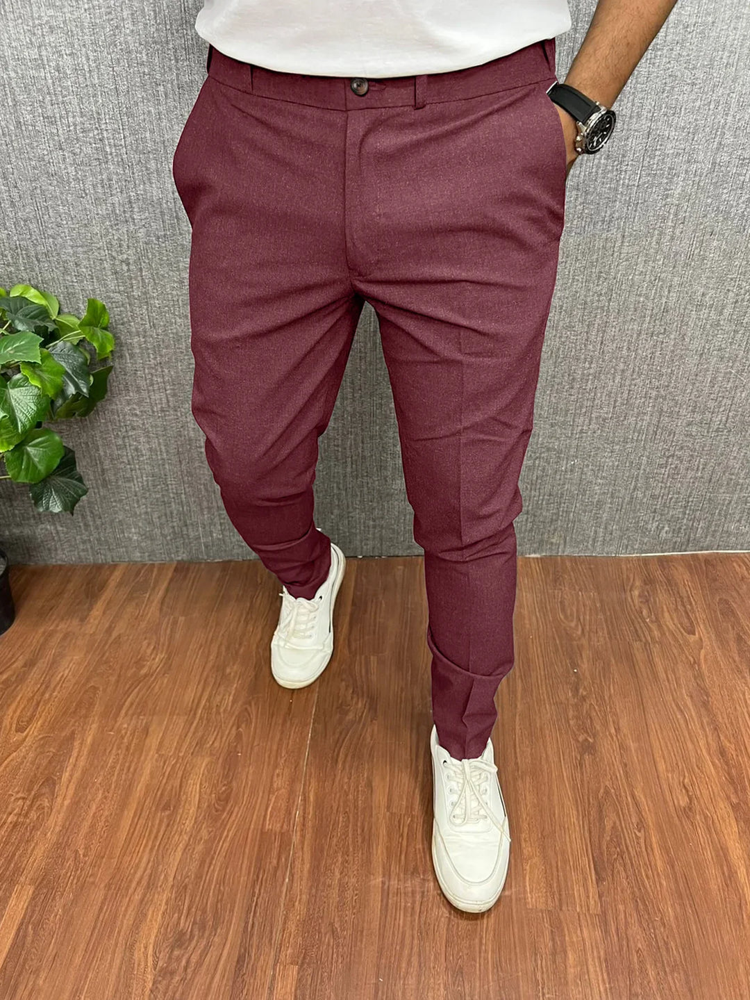 Mens slim fit burgundy formal pants paired with white sneakers and watch on wooden floor