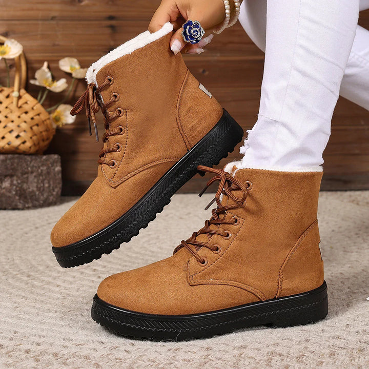 Brown suede winter boots with black soles and white fleece lining worn with white jeans
