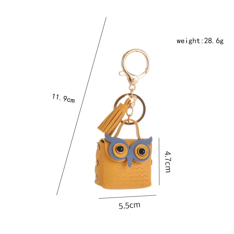 Yellow owl-shaped leather keychain with blue eyes, gold clasp, and tassel, measuring 11.9cm long