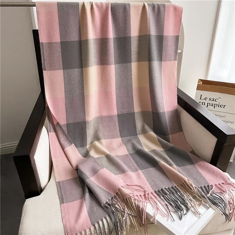 Soft pink, gray, and beige plaid wool throw blanket with fringes draped over white armchair
