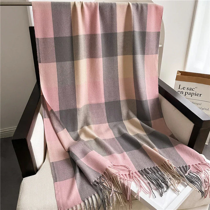 Soft pink, gray, and beige plaid wool throw blanket with fringes draped over white armchair