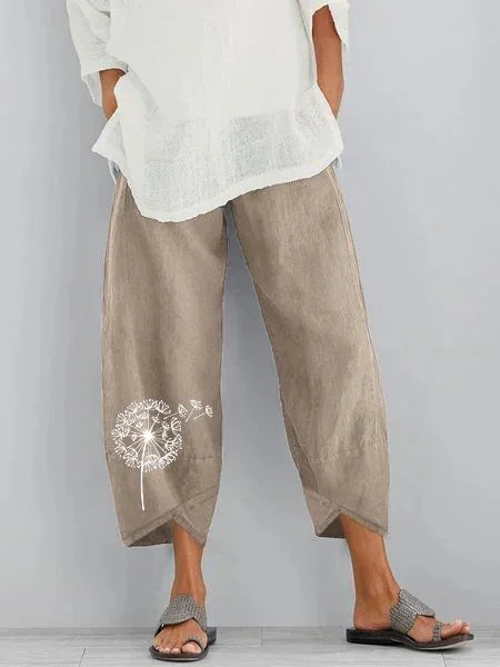Beige wide-leg cotton pants with white dandelion print on leg, paired with white top and sandals