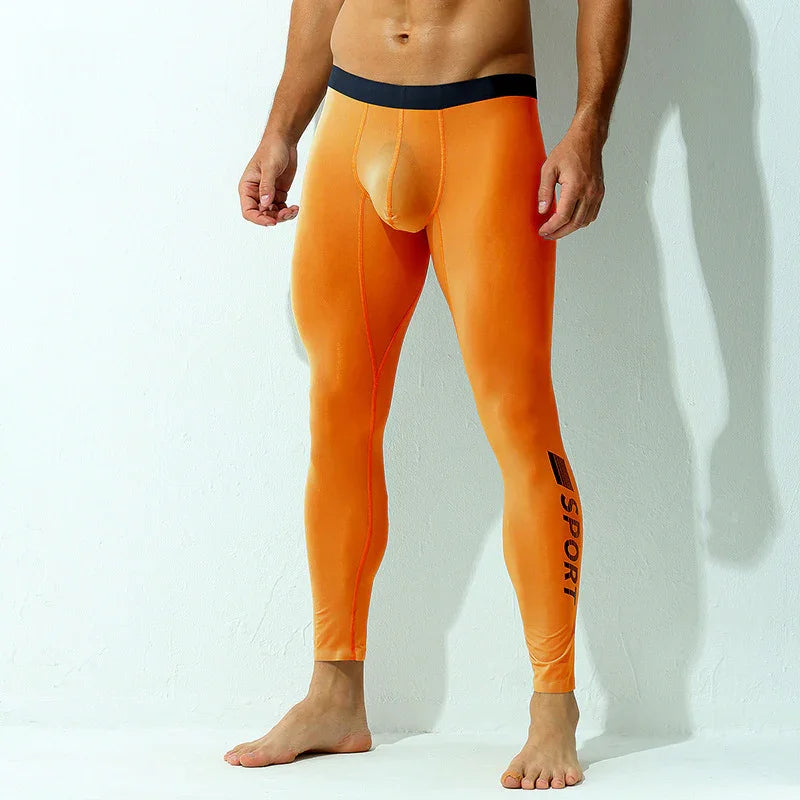 Man wearing bright orange sport leggings with black waistband and SPORT text on leg against white wall