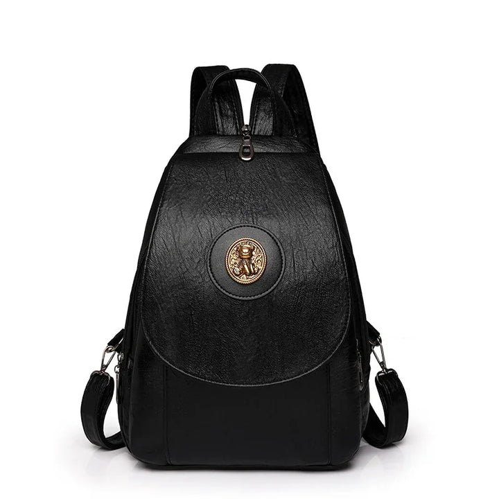black leather backpack with gold emblem, adjustable straps, and top handle against white background