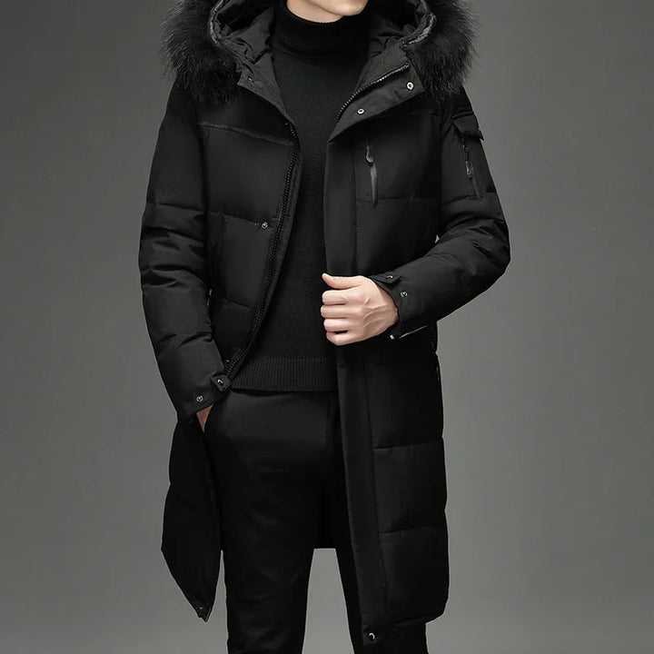 Man wearing a long black padded winter coat with fur hood and black turtleneck sweater