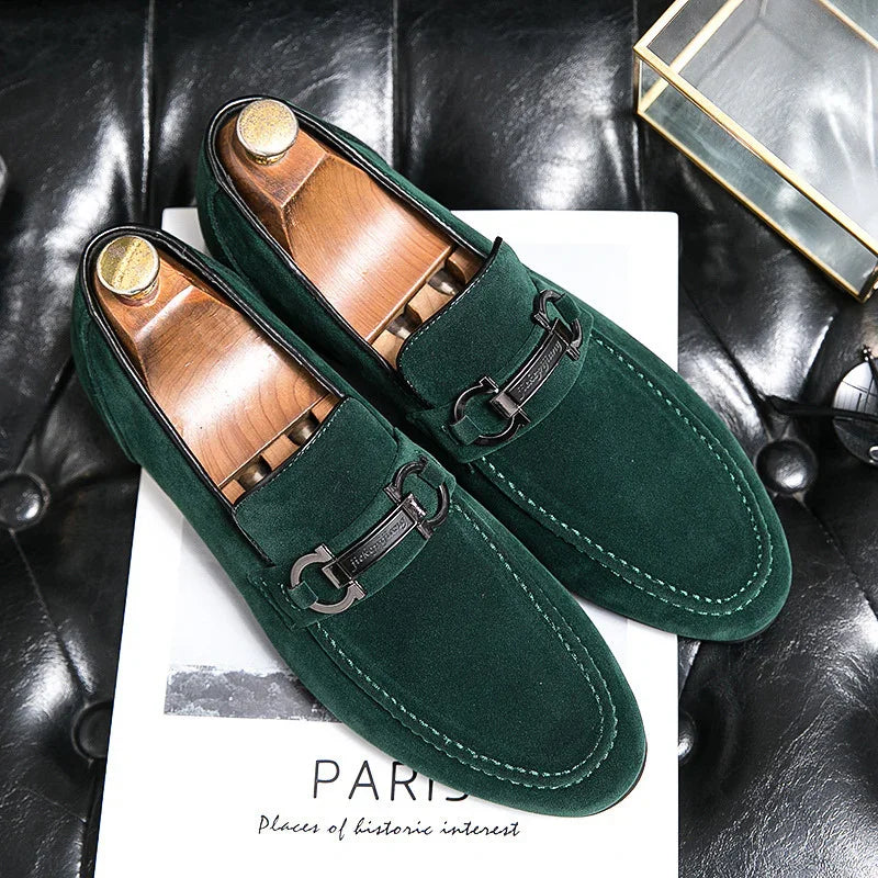 Pair of green suede men's loafers with black metal bit detail on black leather surface