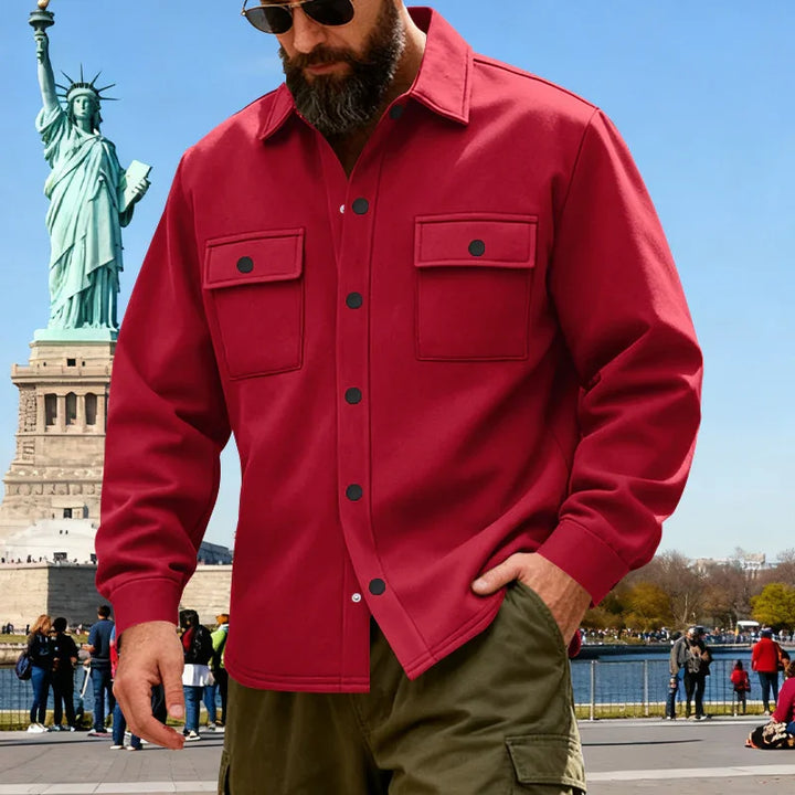 Bearded man wearing red buttoned shirt and sunglasses near Statue of Liberty in clear day